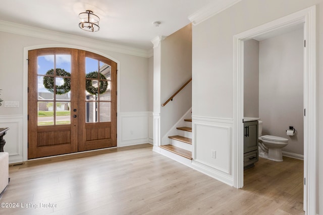 foyer entrance featuring french doors, light wood-type flooring, and ornamental molding