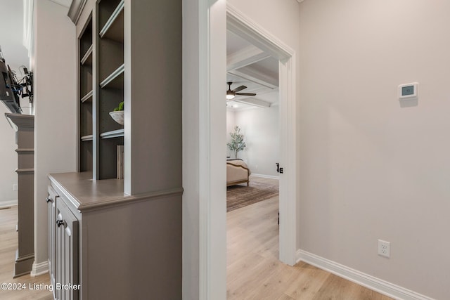 corridor featuring beamed ceiling, coffered ceiling, and light hardwood / wood-style flooring