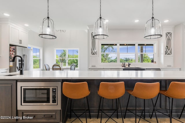 kitchen with hanging light fixtures, plenty of natural light, sink, and white cabinets