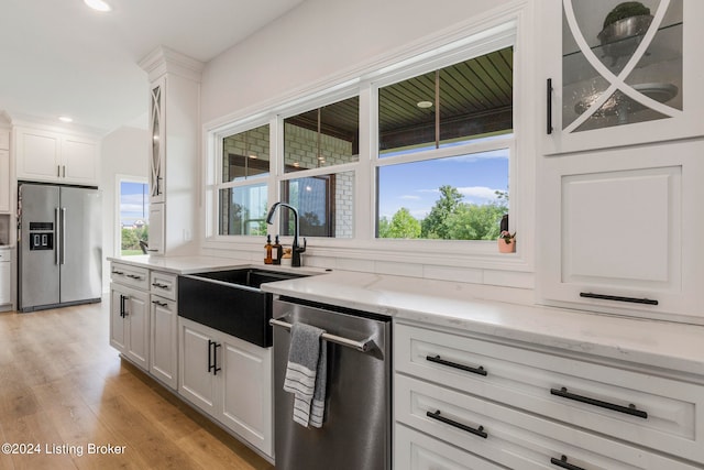 kitchen with white cabinets, appliances with stainless steel finishes, sink, and light hardwood / wood-style flooring