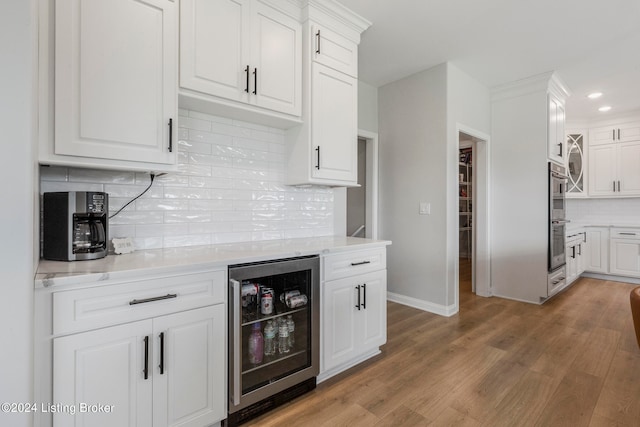 kitchen with white cabinetry, beverage cooler, and hardwood / wood-style flooring