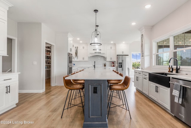 kitchen with light hardwood / wood-style floors, stainless steel appliances, sink, and white cabinetry