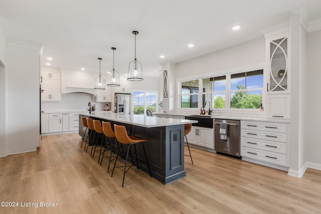 kitchen with a kitchen island, light hardwood / wood-style flooring, stainless steel appliances, and white cabinets