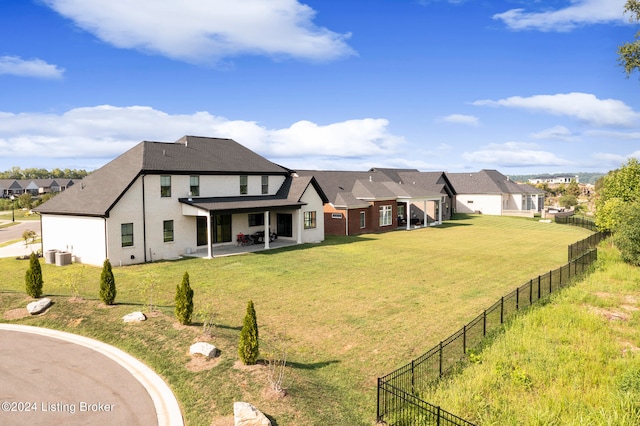 rear view of property featuring a lawn, central AC unit, and a patio area