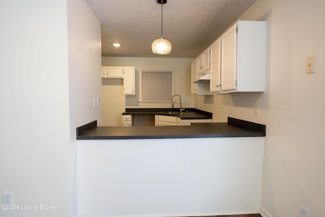 kitchen featuring white cabinets, kitchen peninsula, a textured ceiling, decorative light fixtures, and sink