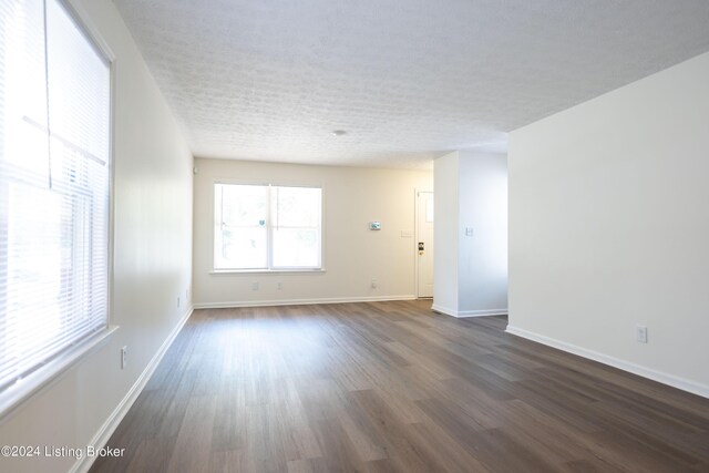 empty room featuring a textured ceiling and dark wood-type flooring