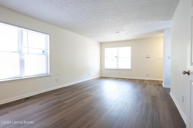 empty room with a textured ceiling and dark wood-type flooring