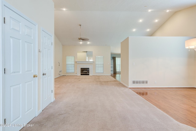 unfurnished living room featuring light wood-type flooring, vaulted ceiling, and a tiled fireplace