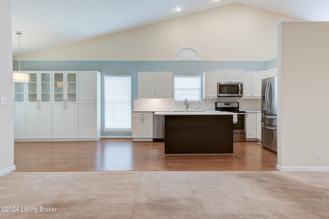 kitchen with white cabinetry, high vaulted ceiling, stainless steel appliances, decorative light fixtures, and hardwood / wood-style flooring