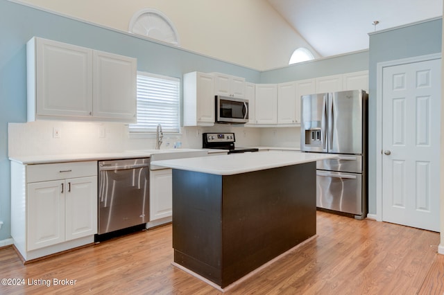 kitchen with stainless steel appliances, white cabinets, light hardwood / wood-style floors, and a kitchen island