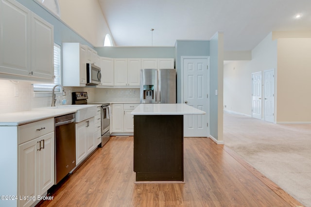 kitchen featuring white cabinets, stainless steel appliances, light wood-type flooring, and a center island