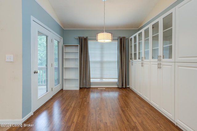 unfurnished dining area featuring dark hardwood / wood-style floors, vaulted ceiling, and crown molding