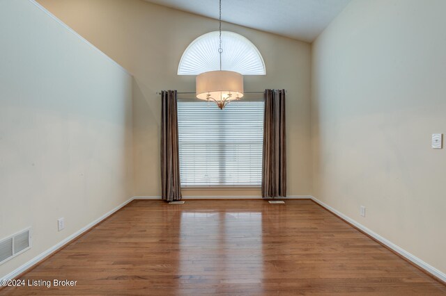 unfurnished room with a notable chandelier, hardwood / wood-style flooring, and a wealth of natural light