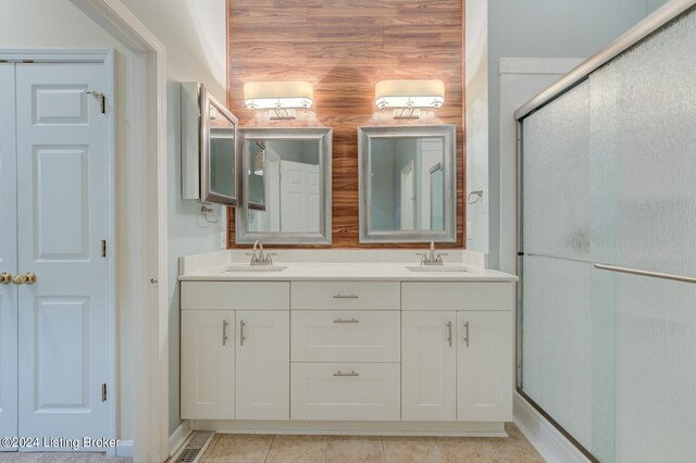 bathroom featuring tile patterned flooring, wood walls, a shower with door, and vanity