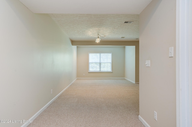 carpeted empty room featuring a textured ceiling