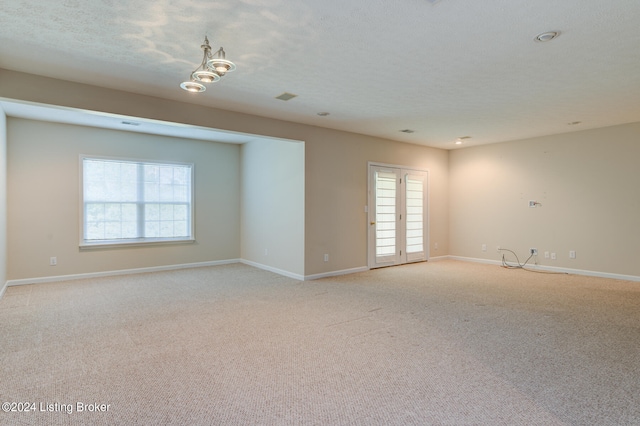 unfurnished room featuring a textured ceiling and light colored carpet