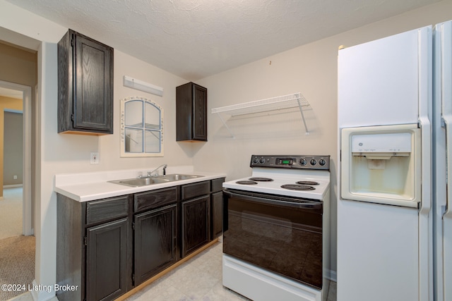 kitchen featuring a textured ceiling, dark brown cabinetry, white appliances, and sink