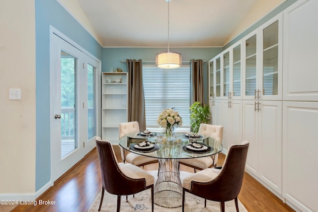 dining space with light hardwood / wood-style flooring, vaulted ceiling, and ornamental molding