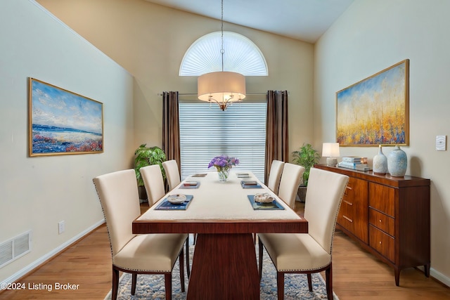 dining area featuring an inviting chandelier, light hardwood / wood-style floors, and high vaulted ceiling