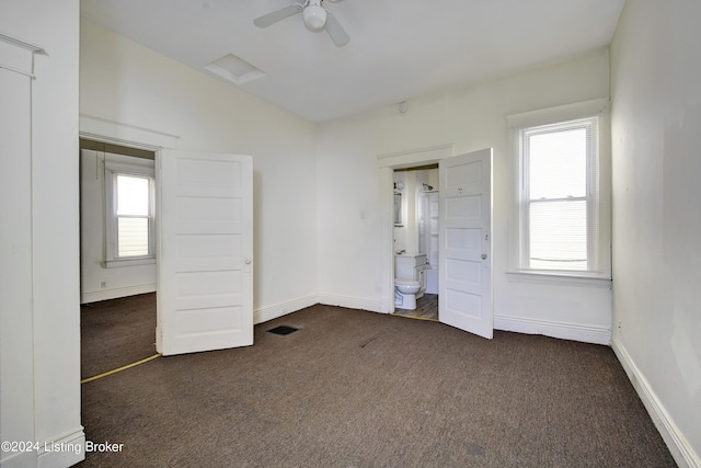 unfurnished bedroom with connected bathroom, dark colored carpet, ceiling fan, and a closet