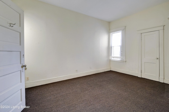 empty room with a baseboard radiator and dark colored carpet