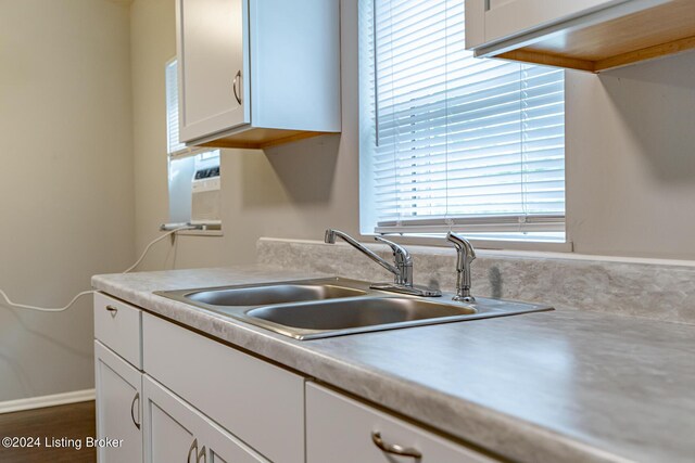 kitchen featuring cooling unit, white cabinetry, and sink