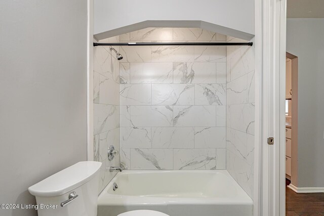 bathroom with wood-type flooring, tiled shower / bath, and toilet