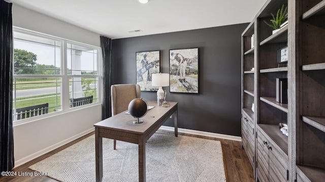 home office with dark hardwood / wood-style flooring and a wealth of natural light