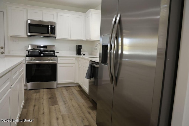 kitchen featuring white cabinetry, appliances with stainless steel finishes, sink, and light wood-type flooring