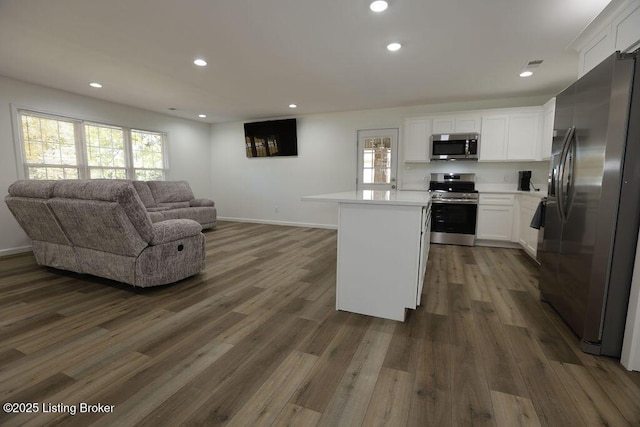 kitchen featuring stainless steel appliances, white cabinetry, a center island, and dark wood-type flooring