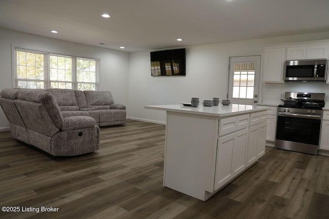 kitchen with dark wood-type flooring, stainless steel appliances, a center island, and white cabinets