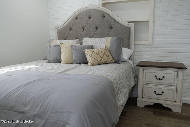 bedroom with brick wall and dark hardwood / wood-style floors