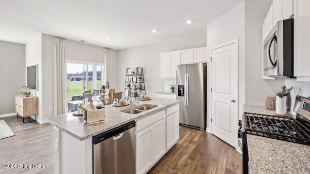 kitchen with white cabinets, a kitchen island with sink, appliances with stainless steel finishes, and light stone countertops