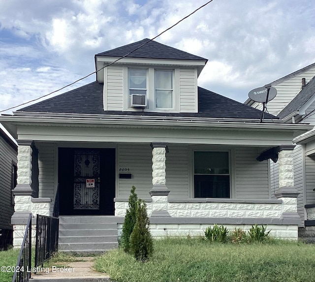 bungalow-style home with cooling unit, a porch, and a shingled roof