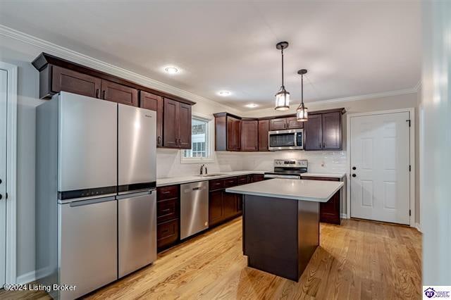 kitchen with pendant lighting, dark brown cabinets, light hardwood / wood-style floors, a center island, and appliances with stainless steel finishes