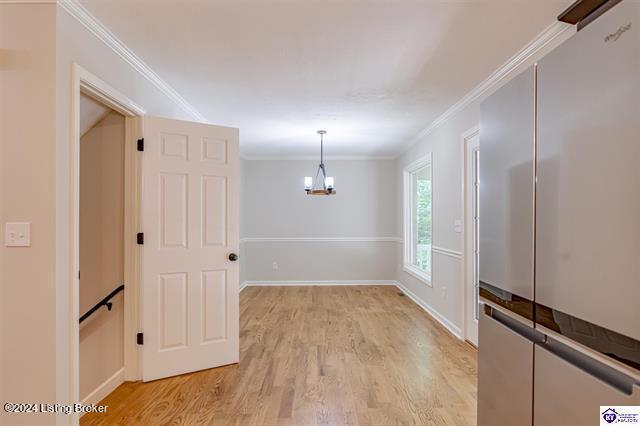 2656 Doe Valley Pkwy, Brandenburg, KY 40108 - unfurnished dining area featuring baseboards, ornamental molding, a chandelier, and light wood-type flooring
