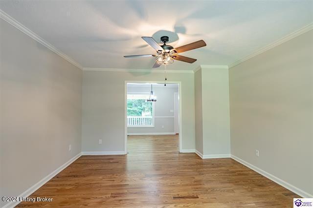 2656 Doe Valley Pkwy, Brandenburg, KY 40108 - spare room featuring ornamental molding, ceiling fan with notable chandelier, baseboards, and wood finished floors