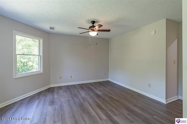 unfurnished room featuring ceiling fan, dark wood-type flooring, and a textured ceiling