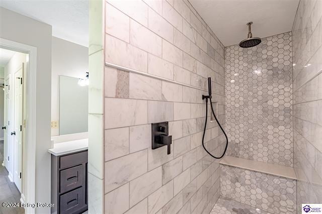 bathroom with vanity and tiled shower