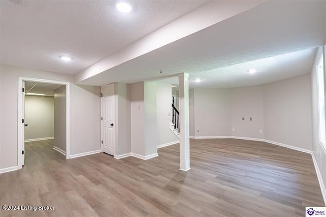 basement with hardwood / wood-style flooring and a textured ceiling