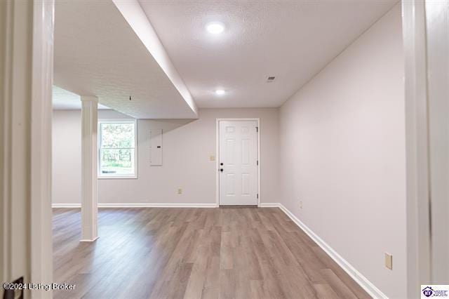 interior space with light hardwood / wood-style floors, electric panel, and a textured ceiling