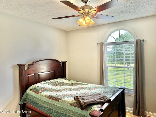 bedroom featuring a textured ceiling, wood-type flooring, and ceiling fan