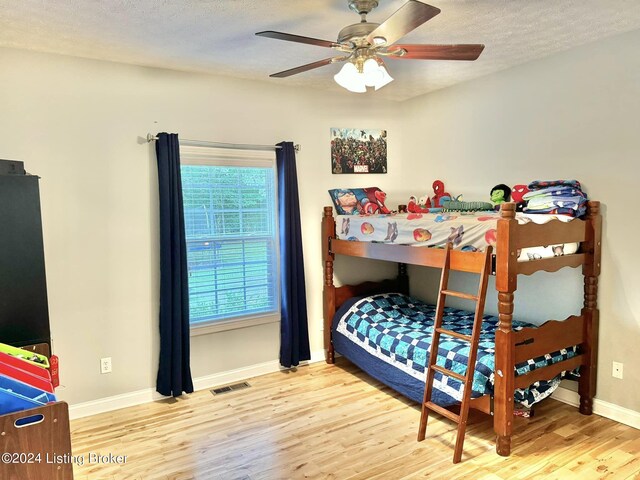 bedroom featuring hardwood / wood-style floors, a textured ceiling, and ceiling fan