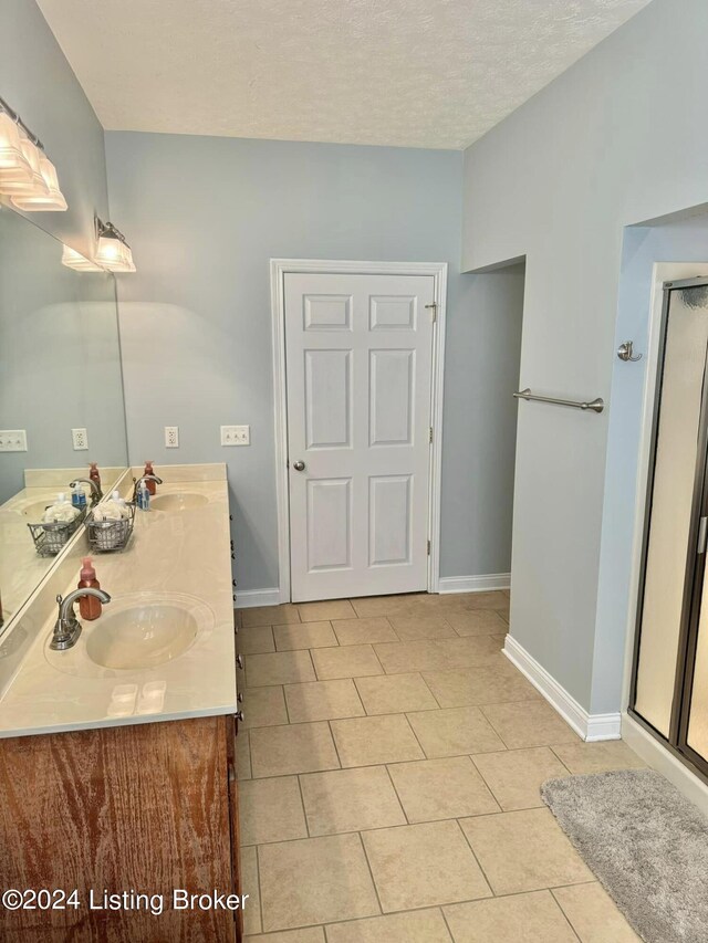 bathroom featuring vanity, tile patterned flooring, a textured ceiling, and an enclosed shower