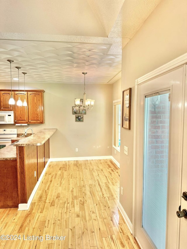 kitchen with white appliances, light stone countertops, a notable chandelier, decorative light fixtures, and light hardwood / wood-style floors