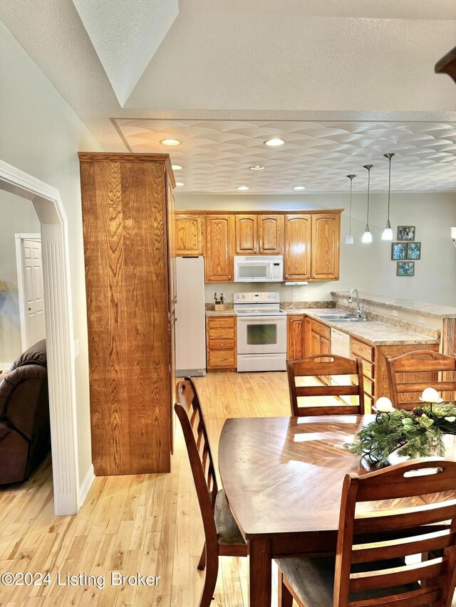 kitchen with white appliances, light wood-type flooring, a textured ceiling, and pendant lighting