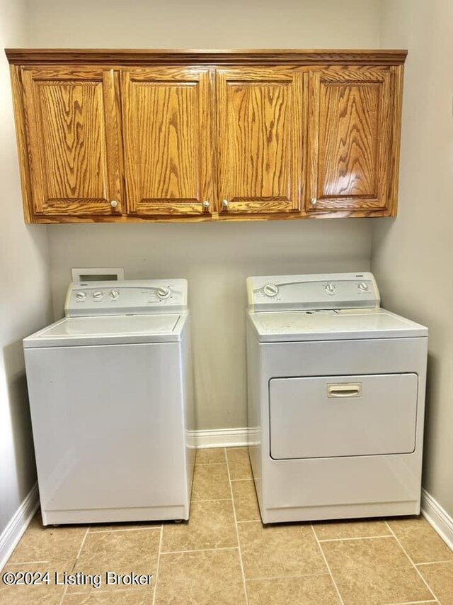 clothes washing area with light tile patterned floors, cabinets, and washer and clothes dryer