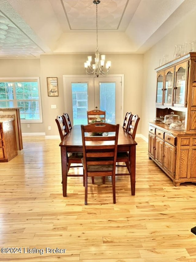 dining room featuring light hardwood / wood-style floors, an inviting chandelier, and a tray ceiling