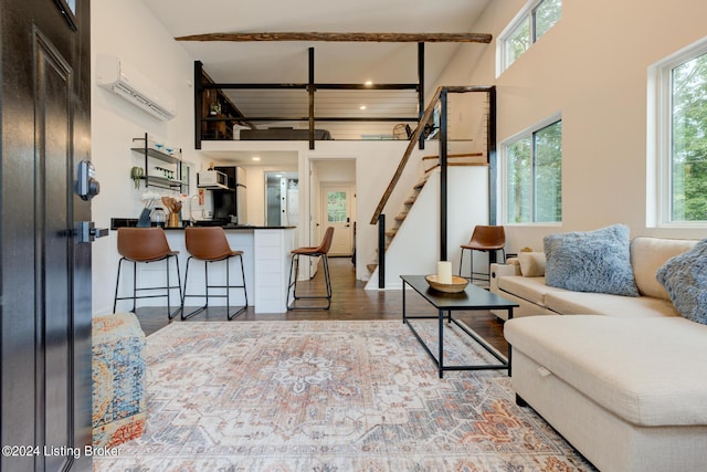 living area with stairs, a high ceiling, wood finished floors, and an AC wall unit