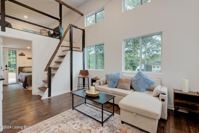 living room featuring a high ceiling, baseboards, stairway, and wood finished floors